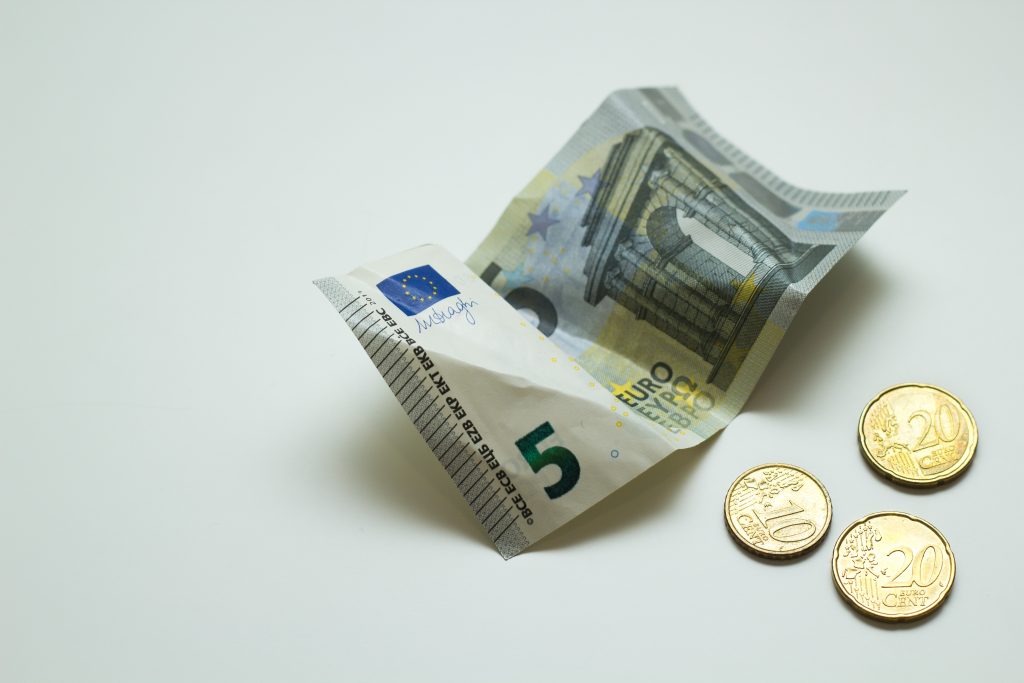 Viiden euron seteli ja kolme kolikkoa pöydällä